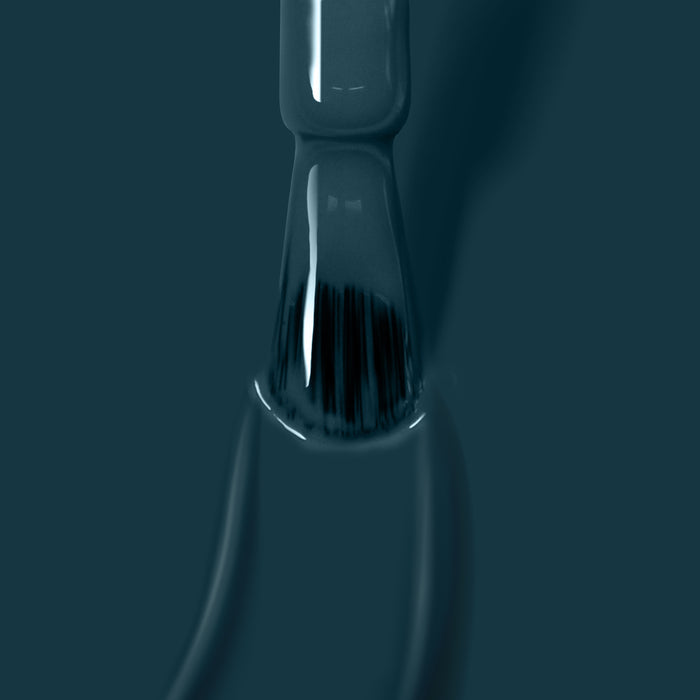 Close-up of a nail polish brush coated with LONDONTOWN's dark-colored, vegan nail polish "Chivvy Along," with the bristles partially visible against a dark green background.