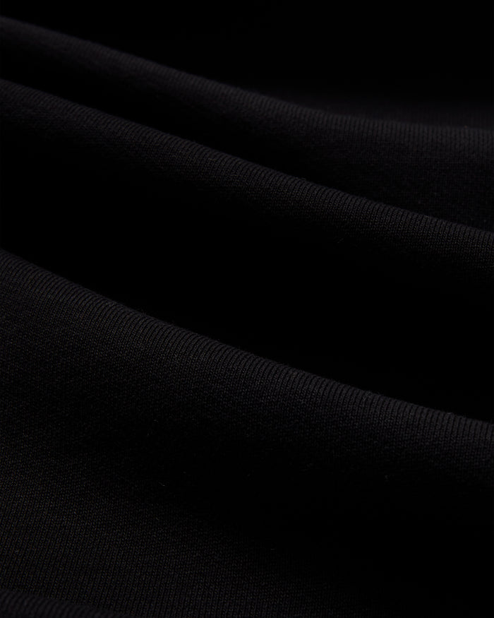 Black crewneck sweatshirt fabric with ribbed knit texture and diagonal folds.