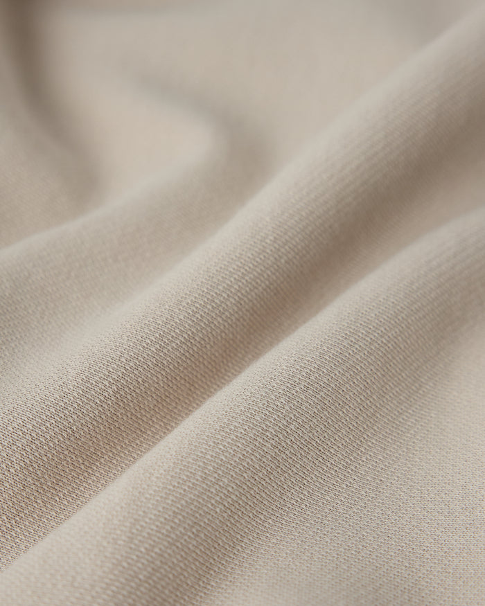 Sandstone sweatshirt fabric with ribbed texture and diagonal folds.
