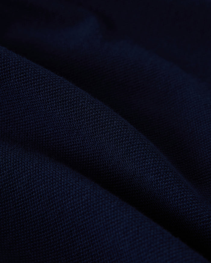 Navy blue polo shirt fabric with ribbed knit texture and diagonal fold detail.
