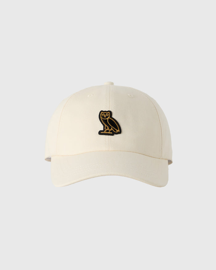 Beige baseball cap with small embroidered owl logo on front.