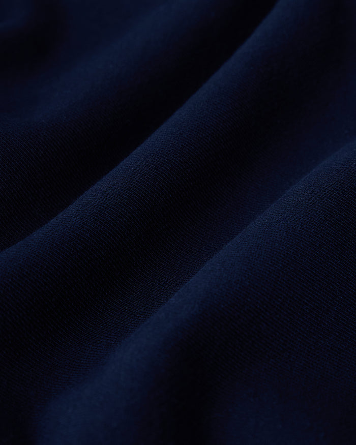 Close-up of navy blue fabric with ribbed texture and soft folds.