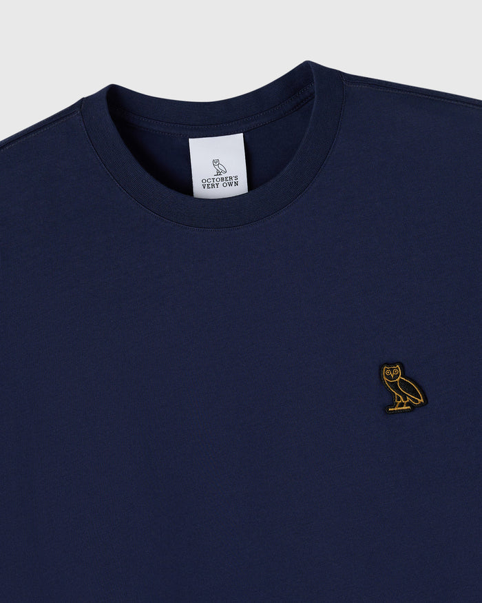 Navy crew neck t-shirt with small gold owl embroidery on chest and brand label at neckline.