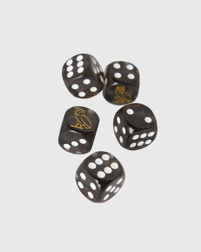 Five black polyhedral dice with white pips and gold owl engravings on select faces.