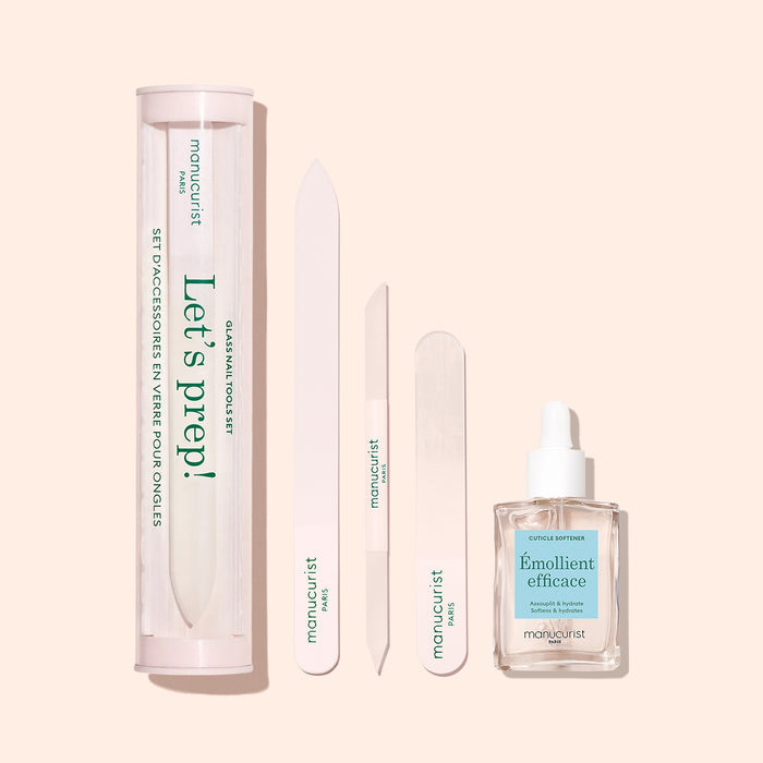The Manucurist Nail Prep Set on a beige background includes nail care essentials: a clear "Let’s prep!" case, pro emery board, two nail files, wooden stick, and cuticle remover with dropper—all neatly arranged.