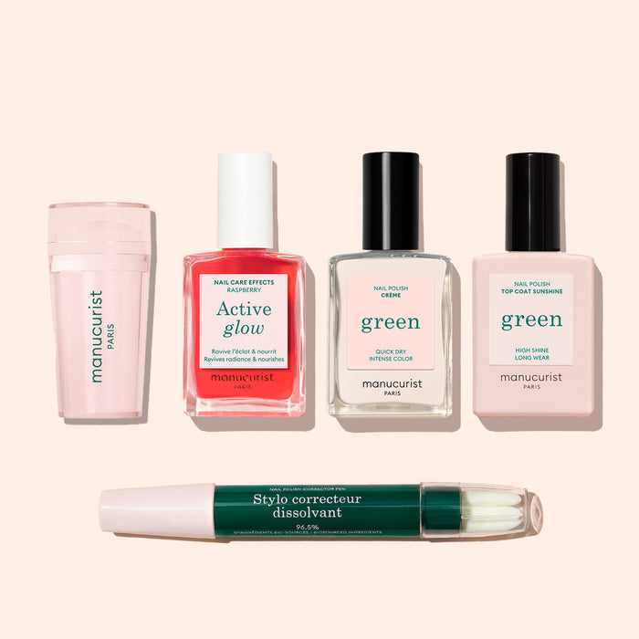 Five manicure products on a light background: Manucurist US Mani stamper, pink cylindrical nail case, red and clear nail polish bottles, a top coat bottle, and a green pen-shaped remover—ideal for flawless or enhanced French tips.