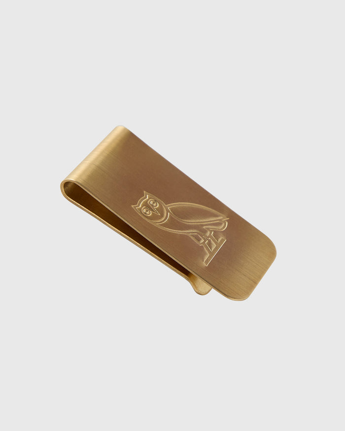 Gold-toned metal money clip with engraved owl design on brushed surface.