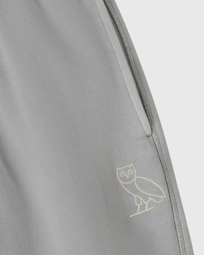Gray sweatpant with open hem and owl embroidery on the leg.