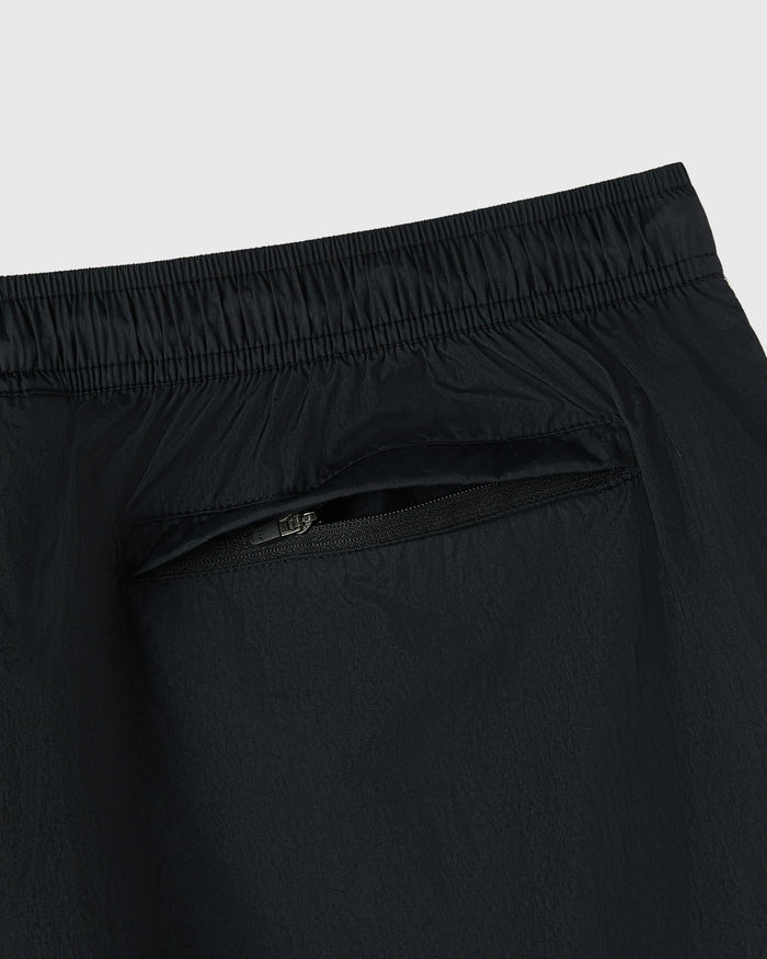 Black nylon track short with elasticated waistband and zippered pocket detail.