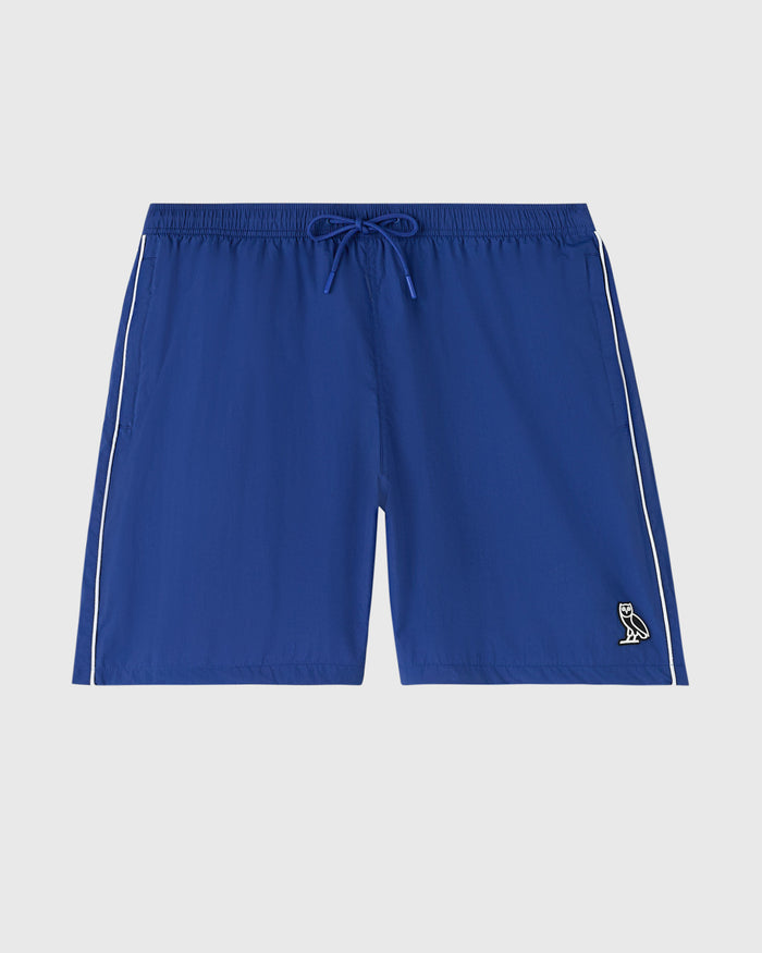 Midnight blue nylon track short with white side stripes, drawstring waist, and small owl logo on leg.