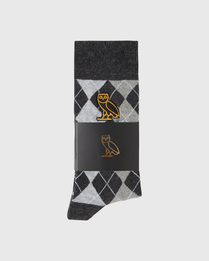 Black sock with argyle pattern in white and gray, featuring a gold owl logo on the calf area.