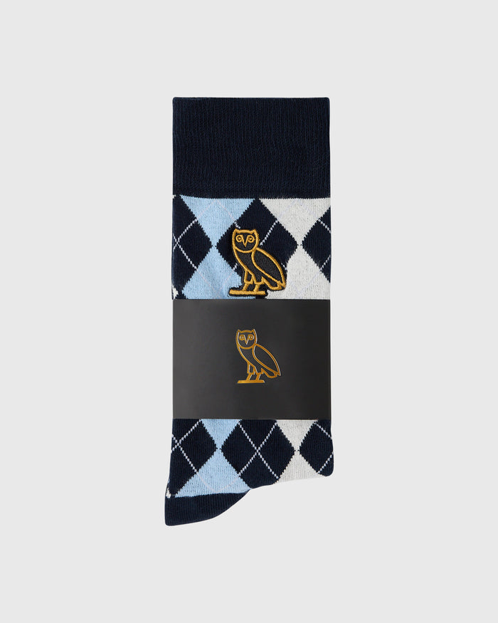 Light blue, black, and white argyle golf sock with gold owl emblem and navy cuff.