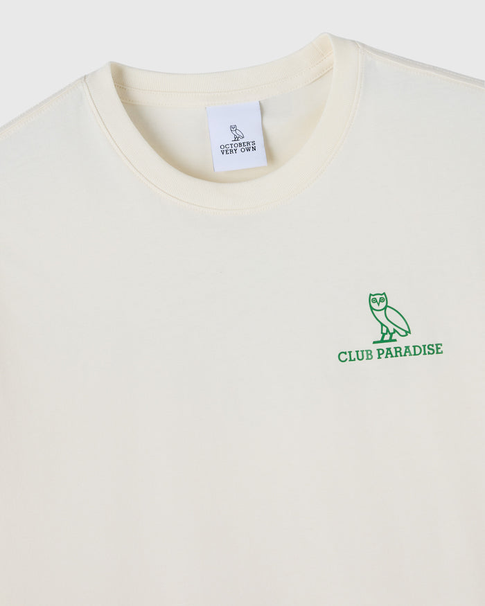 Cream-colored t-shirt with green owl and "Club Paradise" text on chest, OVO label visible at neckline.