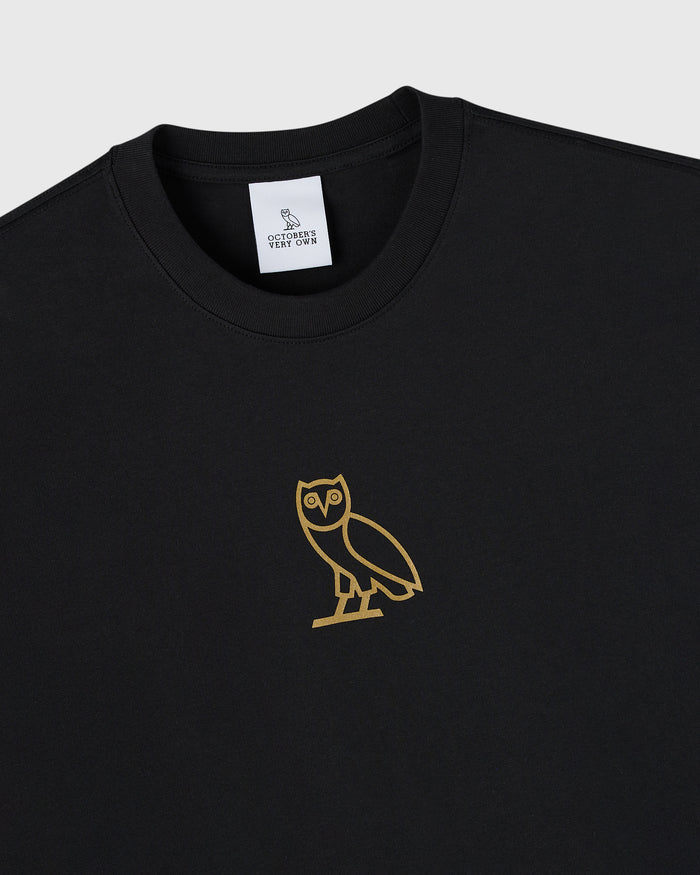 Black crewneck t-shirt with gold owl graphic on chest and brand label on neckline.