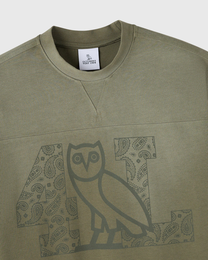 Olive green long-sleeve tee with crew neckline and owl graphic print on front chest.