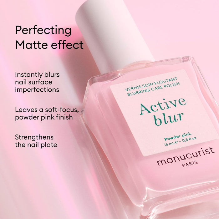 A pink bottle of Manucurist Active™ Blur polish rests on a pink background, with text emphasizing its flawless matte finish, blurring and soft-focus effect, and nail-strengthening benefits—making it the ultimate blurring care polish for healthier-looking nails.
