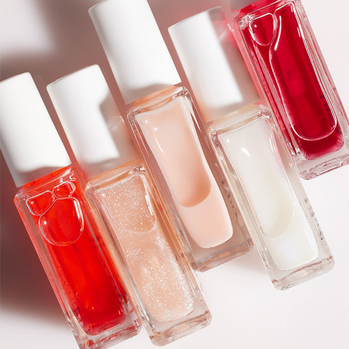 Six bottles of Manucurist Active™ Duo nail polish in red, pink, peach, glitter, and white shades are arranged diagonally on a light surface. Each has a white cap and clear rectangular glass—ideal for natural nails or use with your favorite nail repair treatment.