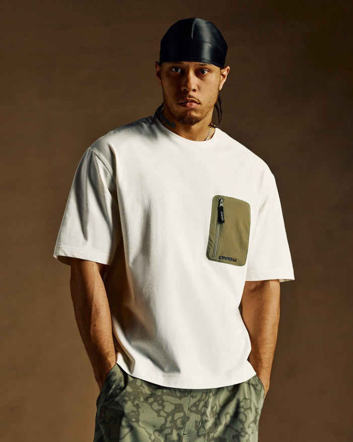 Cream t-shirt with olive green utility pocket on chest, worn with matching patterned pants.