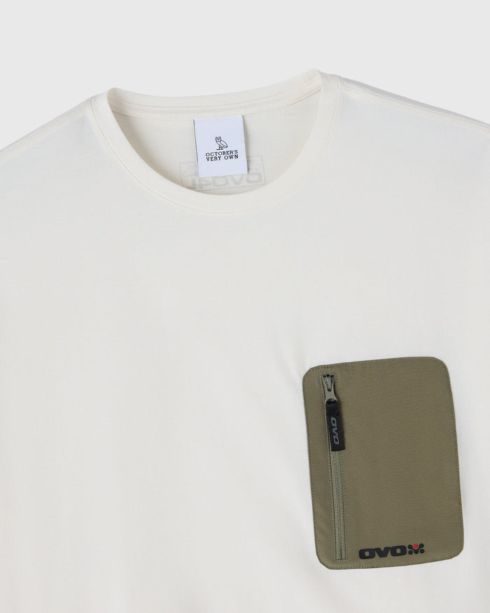 Cream crew-neck t-shirt with olive green zippered pocket on chest.