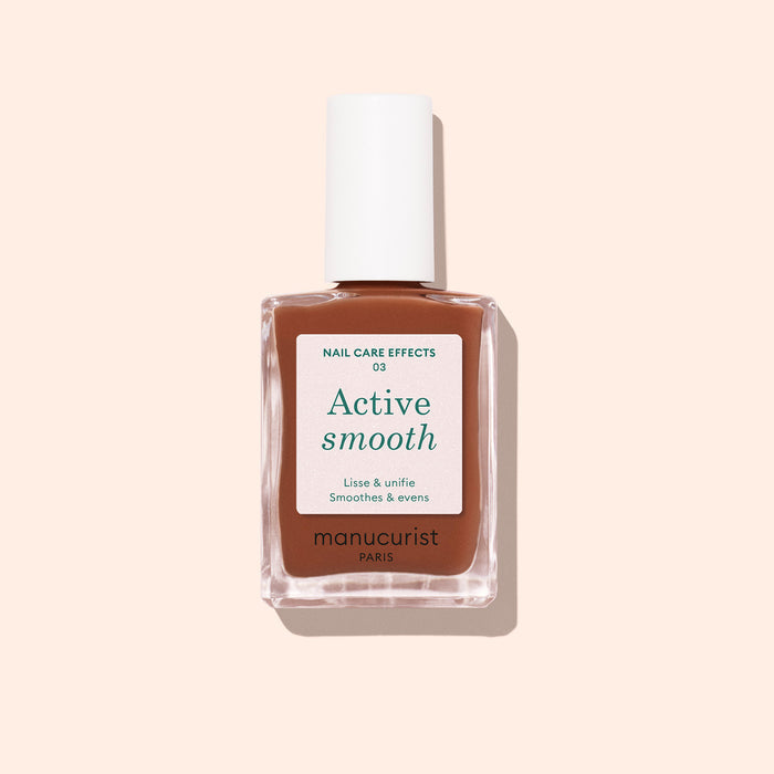 A bottle of Manucurist Active Smooth 03 nail treatment with a white cap, clear glass bottle, and beige-brown label is shown against a pale pink background.