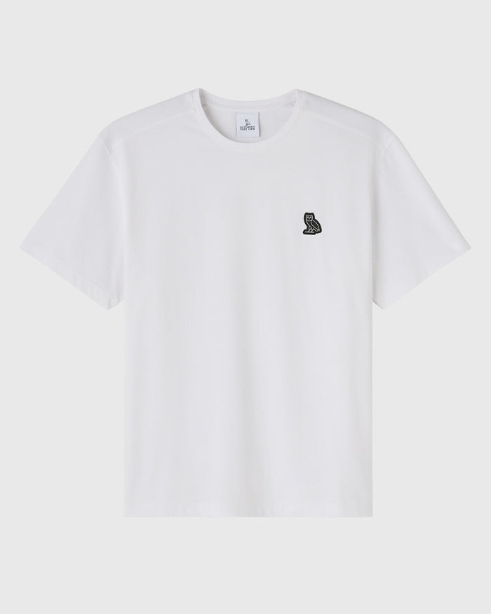 White crewneck t-shirt with small black owl emblem on chest.