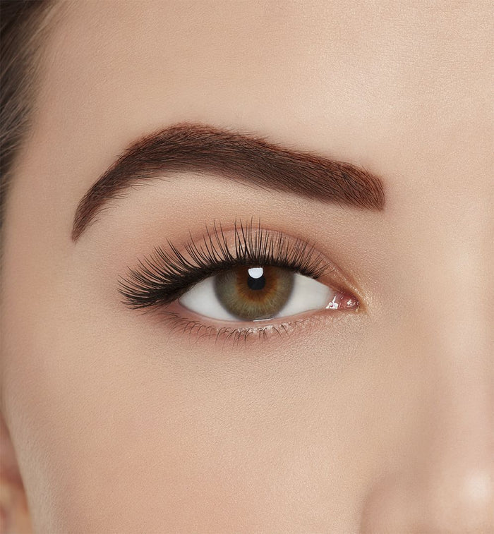 : A model with one eye open wearing Ardell Aqua Lashes 340 upper false lashes to show how they look on the eye