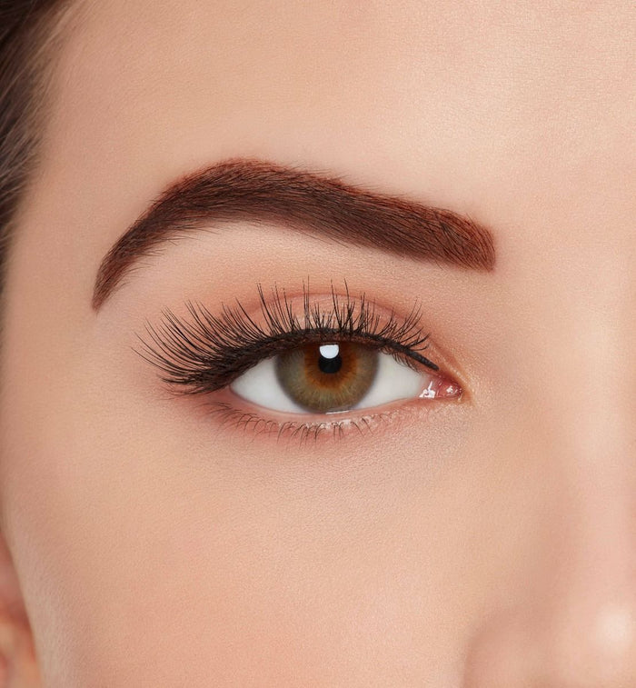 A model with one eye open wearing Ardell Aqua Lashes 341 upper false lashes to show how they look on the eye