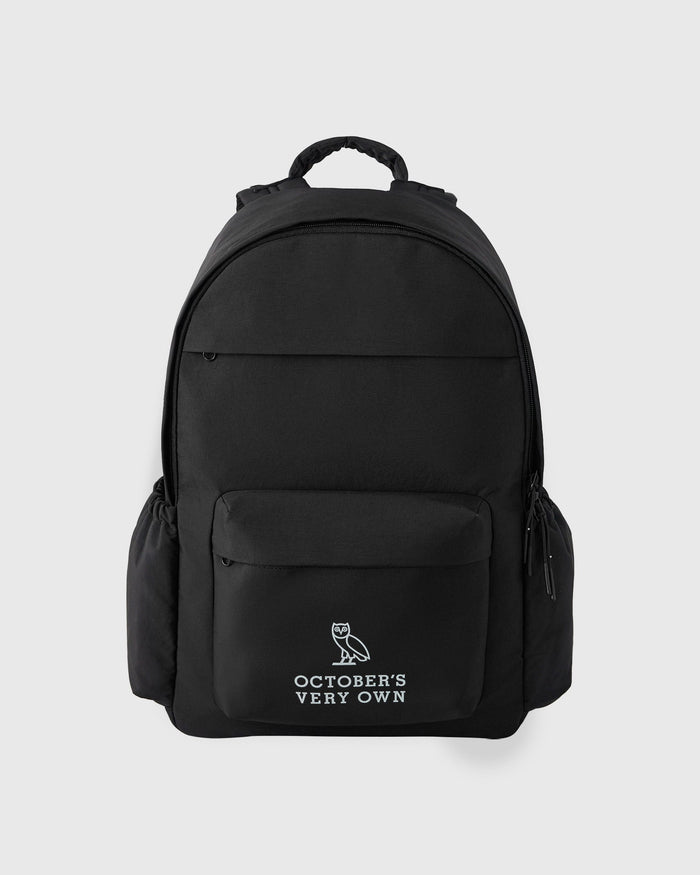Black backpack with padded straps, multiple compartments, and owl logo with "October's Very Own" text on front pocket.