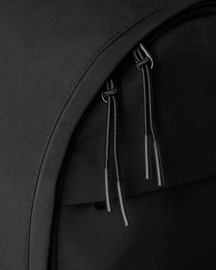 Black backpack with two padded shoulder straps and metal hardware detail on the main compartment.