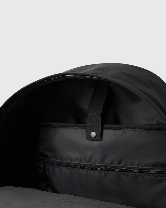 Black backpack with open main compartment, interior zipper pocket, and padded shoulder straps visible from above.