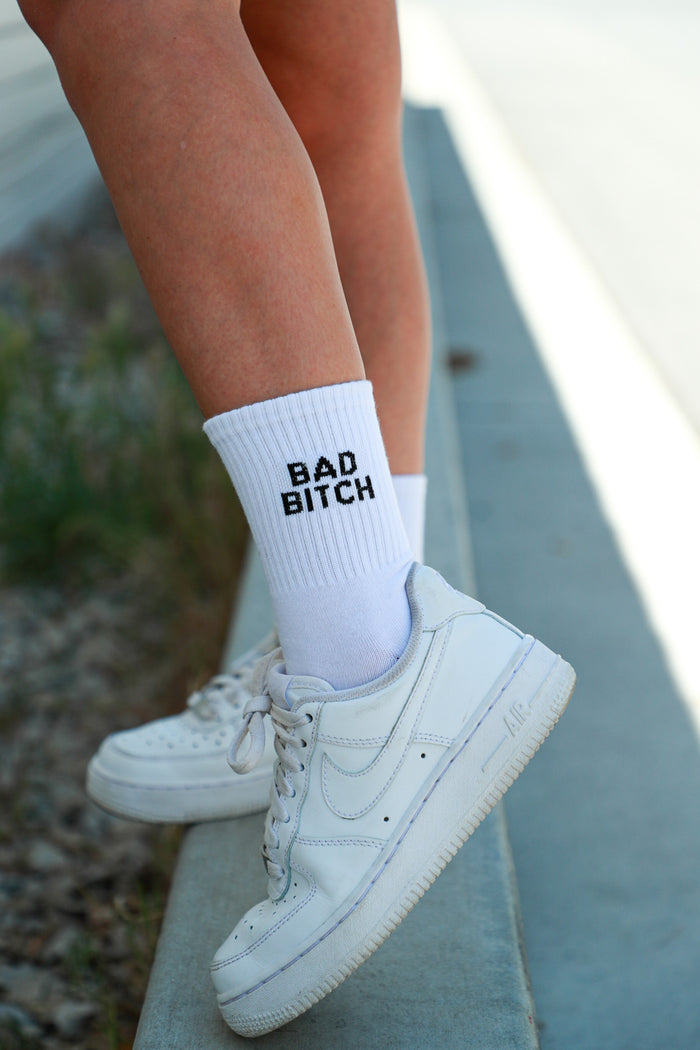 white crewnecks embroidered with "bad bitch" in black text