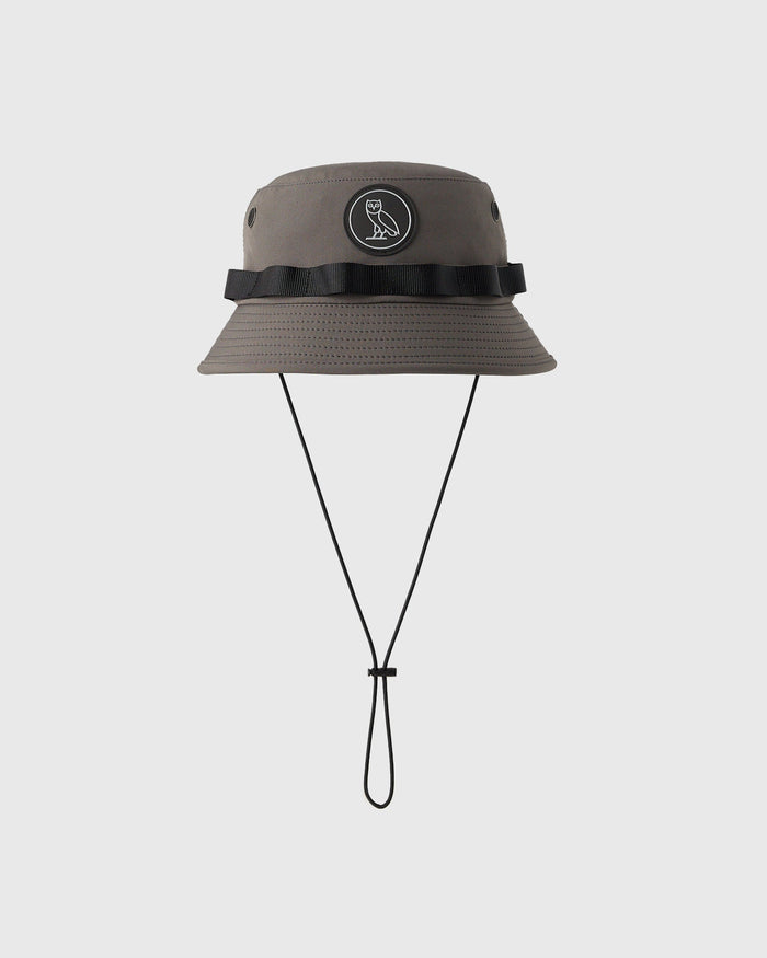 Steel gray boonie hat with black grosgrain band, circular emblem, ventilation eyelets, and black chin cord.