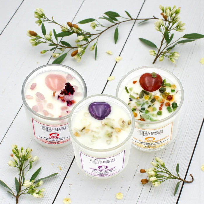Three crystal candles on a white wooden surface with floral decorations.