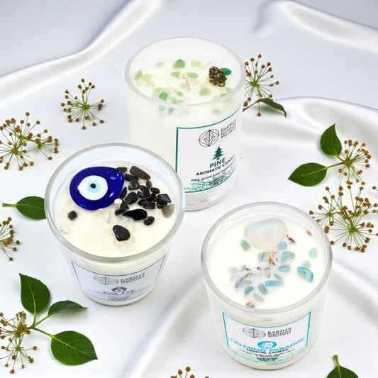 Three candles with decorative elements on a white tray with green leaves