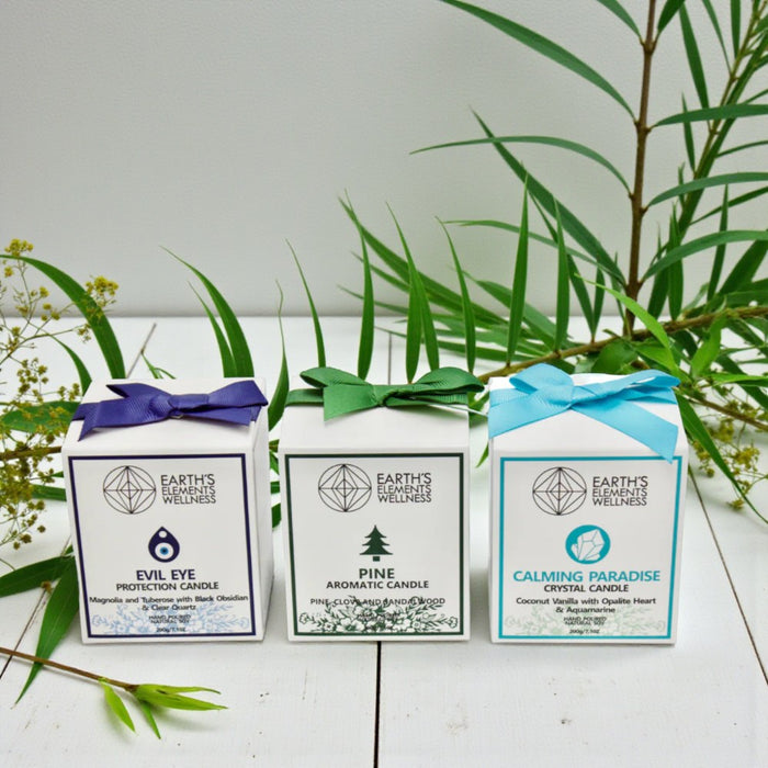 Three Earths Element Wellness candle boxes with greenery in the background