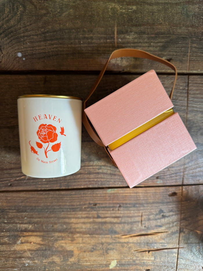 Pink gift box with a gold ribbon and a white mug with a red design on a wooden surface