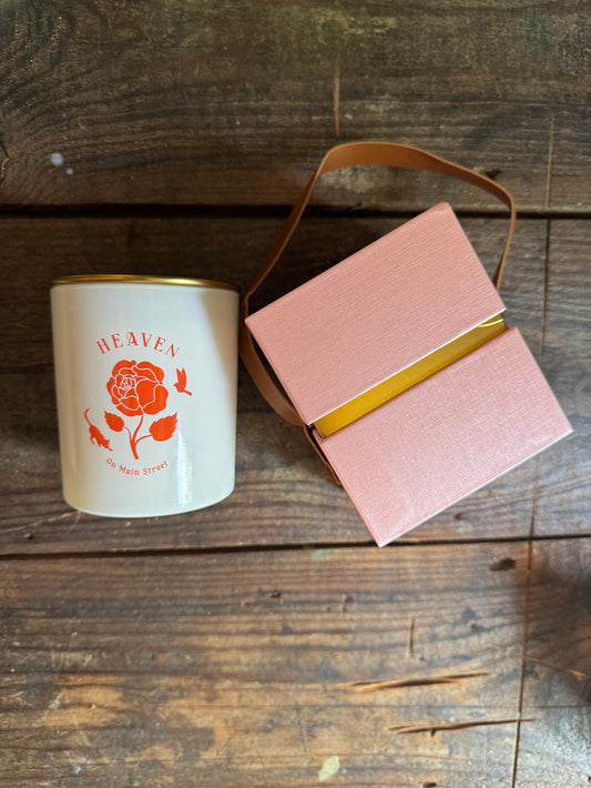 Pink gift box with a gold ribbon and a white mug with a red design on a wooden surface