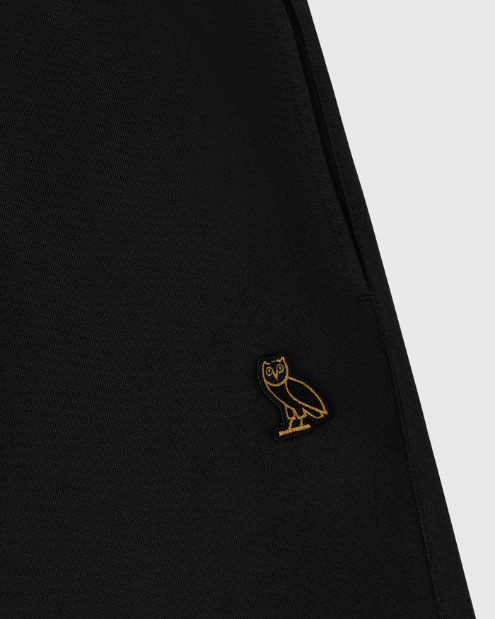 Black sweatpant with small gold owl embroidery on thigh and open hem design.