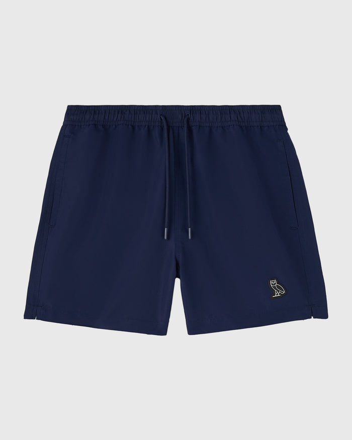 Navy swim shorts with drawstring waist, side pockets, and small embroidered logo on leg.