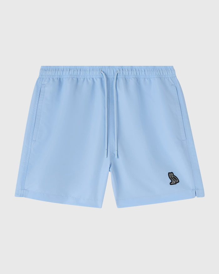 Light blue swim shorts with drawstring waist, side pockets, and small embroidered logo on thigh.