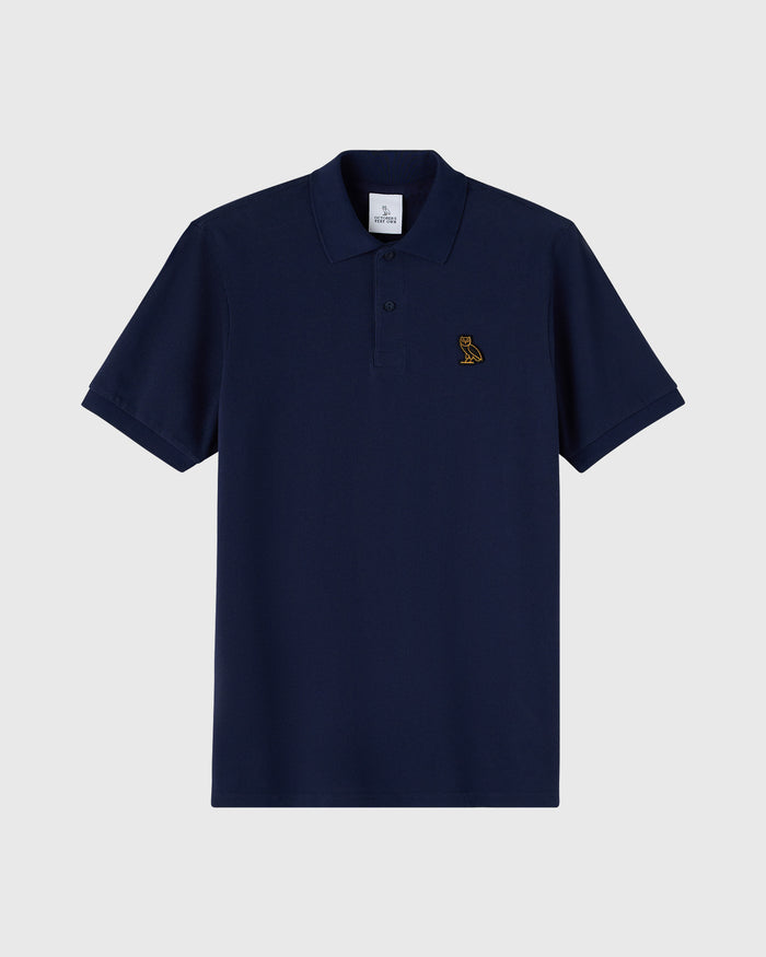 Navy polo shirt with short sleeves, collar, and small gold owl emblem on chest.