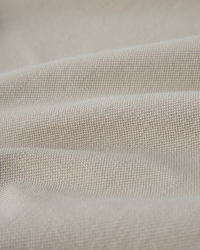 Close-up of sandstone-colored polo fabric showing textured knit weave.