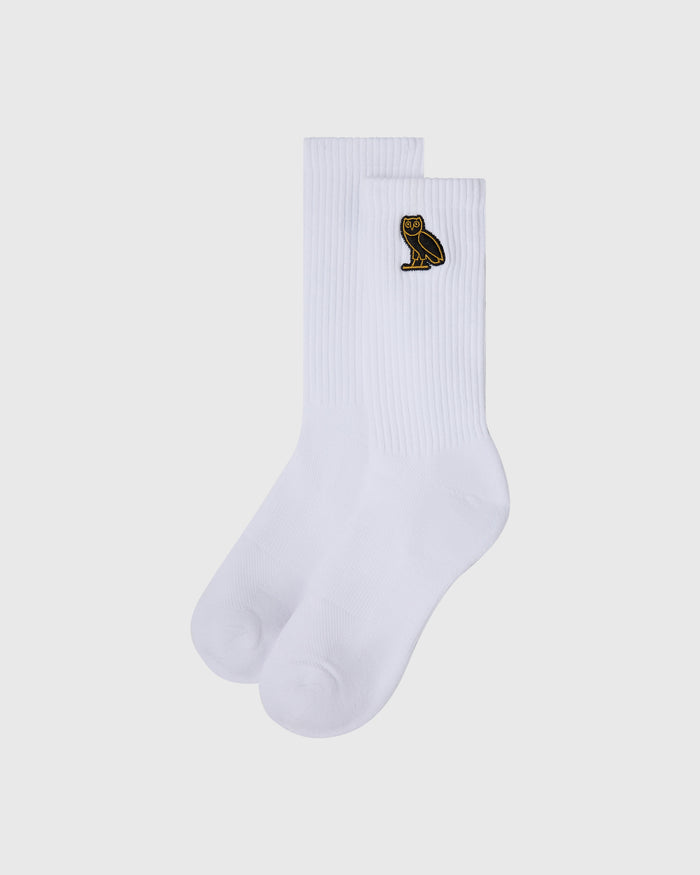 Pair of white ribbed crew socks with small gold owl embroidered on the cuff.