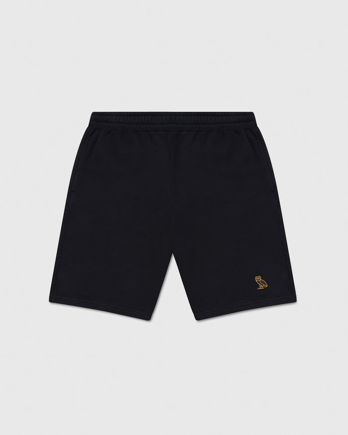 Black sweatshorts with elastic waistband and small gold owl embroidery on right leg.