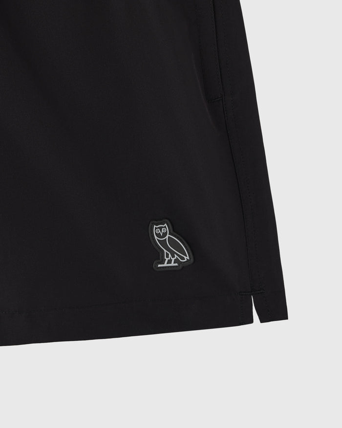 Black swim short with small owl emblem on leg.