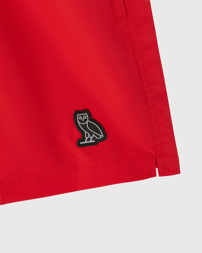 Red swim short with black owl embroidered logo on front.