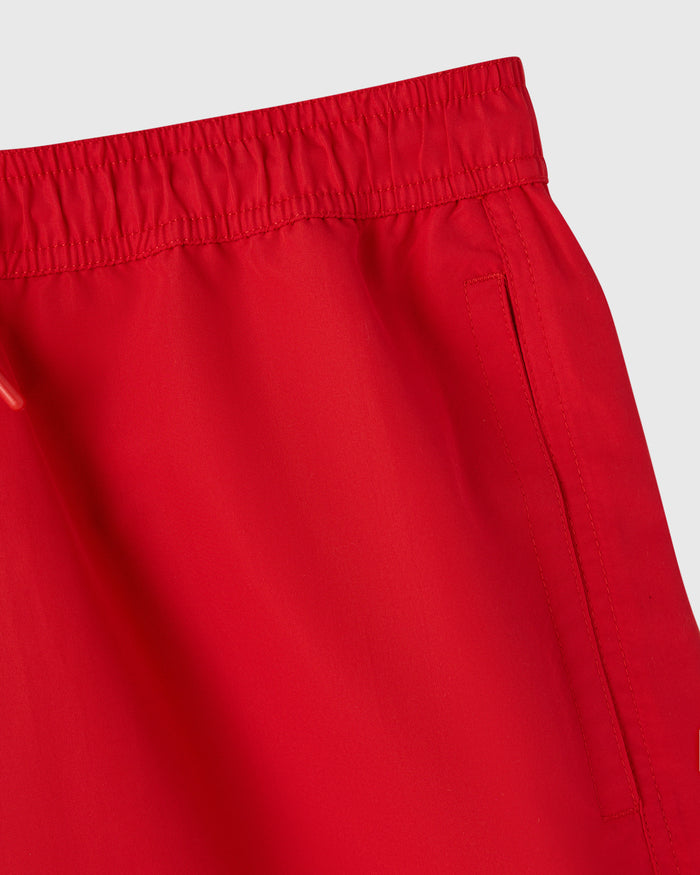 Red swim short with elastic waistband and side pocket detail.