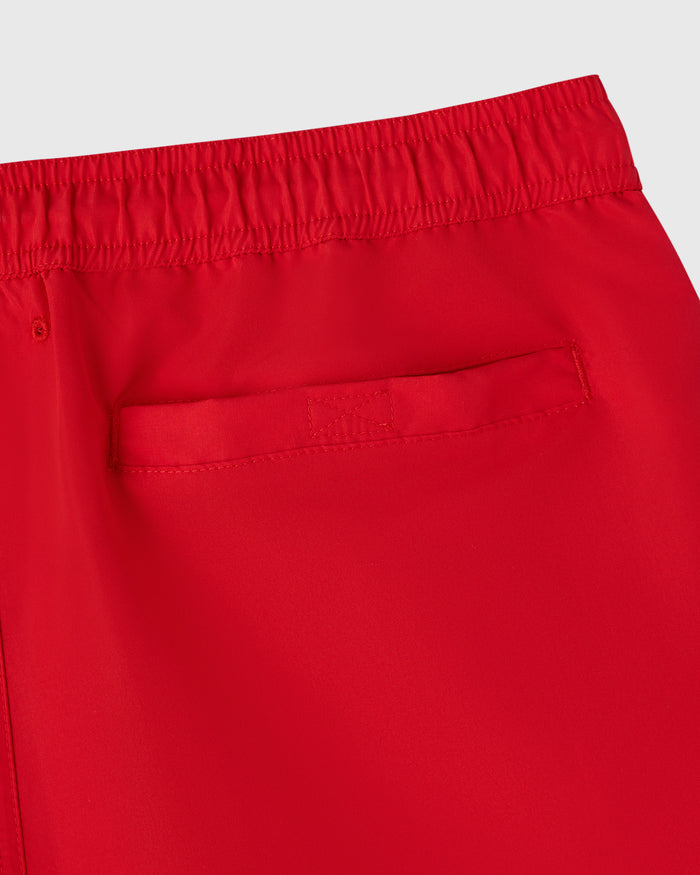 Red swim shorts with elastic waistband and side pocket detail.