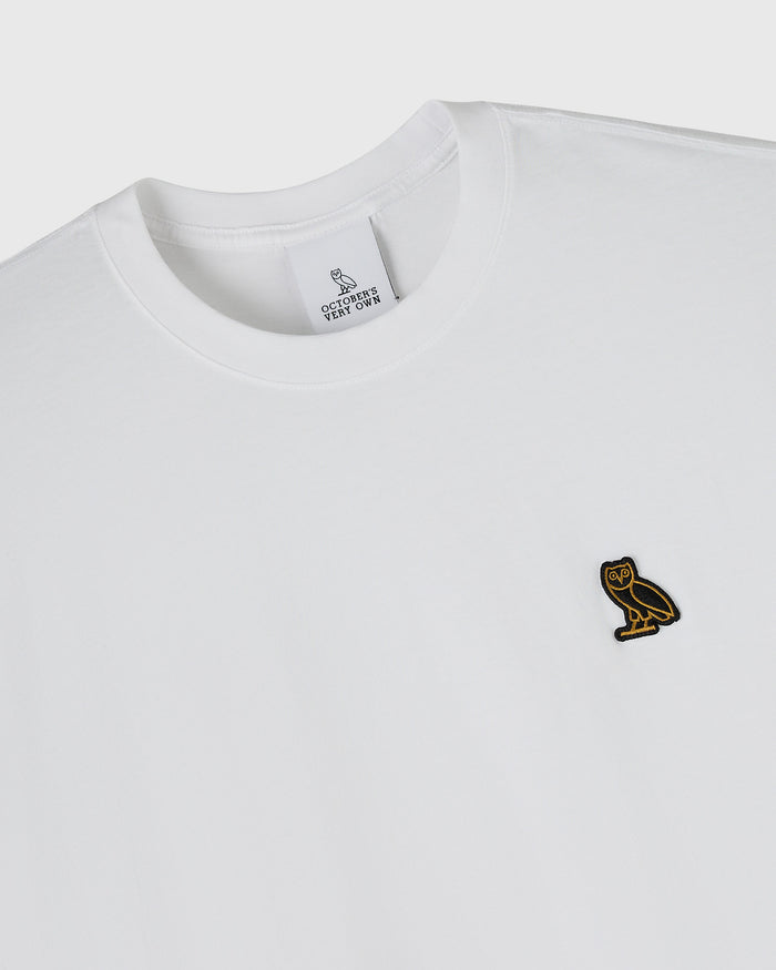 White crew neck t-shirt with small gold owl embroidered on chest and neck tag visible.
