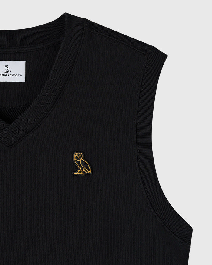 Black sleeveless vest with ribbed edges and small gold owl embroidery on chest.